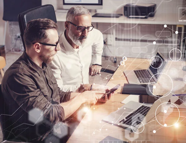 Zwei Mitarbeiter am Schreibtisch arbeiten gemeinsam an den Daten