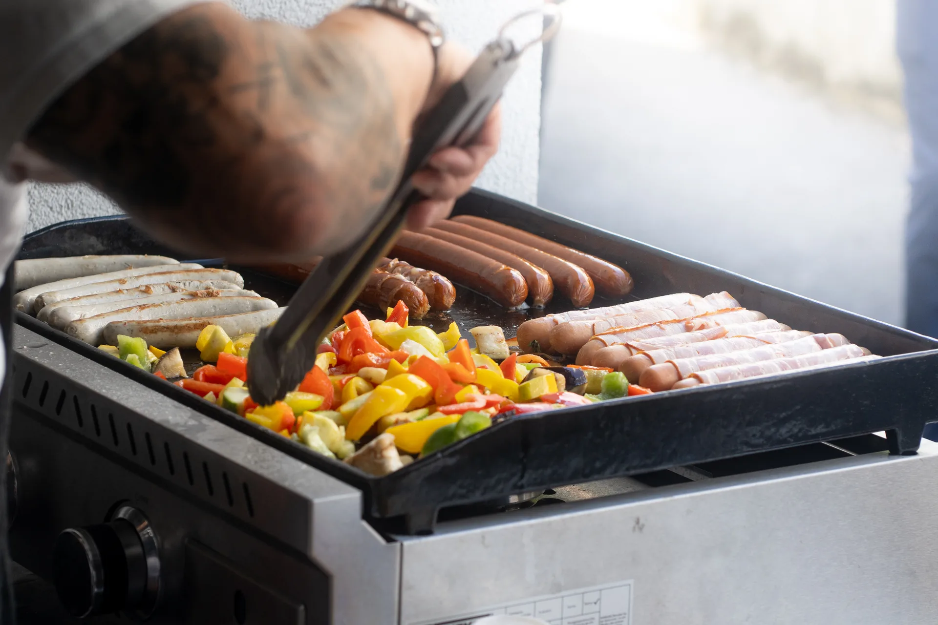 Würste und Grillgemüse auf einer Grillplatte beim Firmengrillen